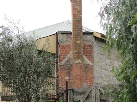 Brick chimney at chamfered corner, possibly a former entrance.