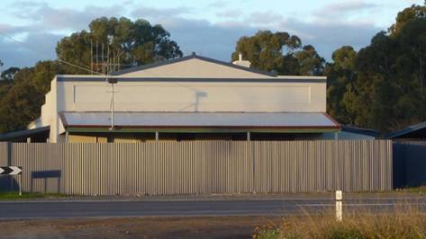 Former Old House at Home Hotel, west elevation, note tall corrugated sheet metal boundary fence