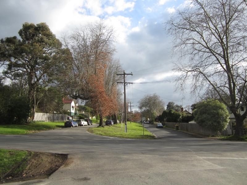 Symons St looking west from Crowley Rd, Green St showing the centre verge with its mature tree plantings and sloping topography. 24 Symons St (contributory) is at left.