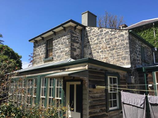 Northwest corner of bluestone fabric, showing two-storey skillion-roof portion, with the enclosed timber-framed verandah of the north elevation in foreground.