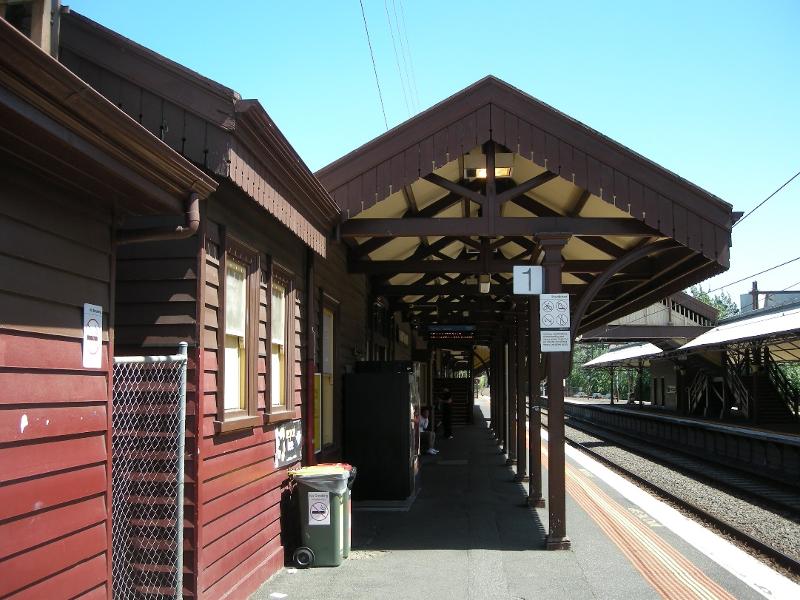 Looking southward along Platform 1 at its buildings and canopy - the canopy timber king-post trusses and support brackets of bent rail are visible