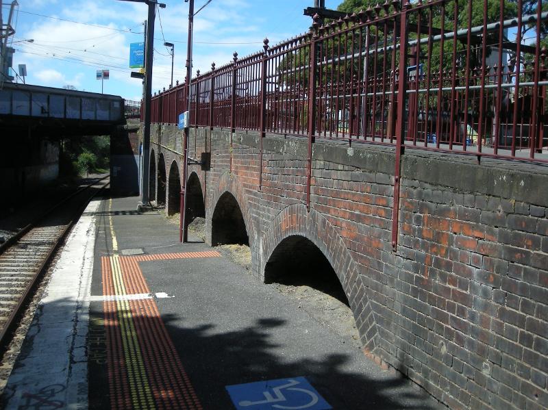 Looking north along Platform 3 at the west-facing brick wall beneath the walkway